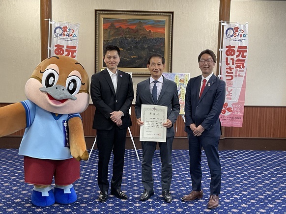 コーナン商事株式会社 疋田代表取締役社長、もずやん、水野教育長と記念写真を撮影する知事