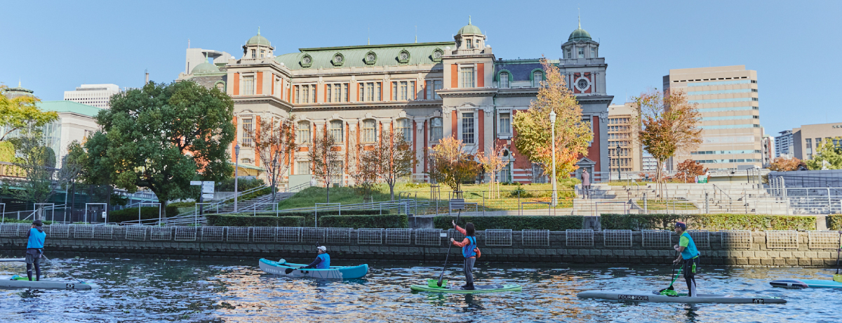 大阪市中央公会堂前の川で、1人乗りサップボードに乗っている参加者たちの様子