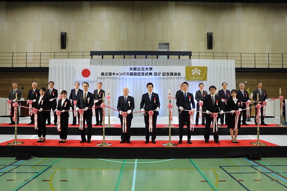 大学関係者、来賓とともにテープカットをする知事