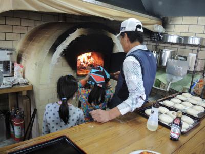 小学生が石窯にピザを入れている様子