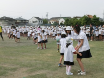 芝生の上で縦割り活動の一つである「なかよし朝礼」で、ゲームをしている子どもたち