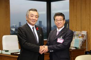 松本国家公安委員会委員長（左）と握手する松井知事（右）