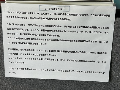 【写真】掲示物「レッドリボンは、ヨーロッパに伝承される風習。病気や事故で人生を全うできなかった人々への追悼の気持を表すもの。」