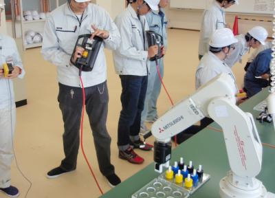 初めて触るロボットのティーチングボックスです。「このボタンをおして・・・」