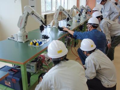 ロボットでワークをつかみ、黒い台のセンサーで色判別をしている実習風景です。