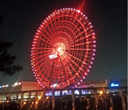 観覧車がオレンジ色にライトアップされている写真
